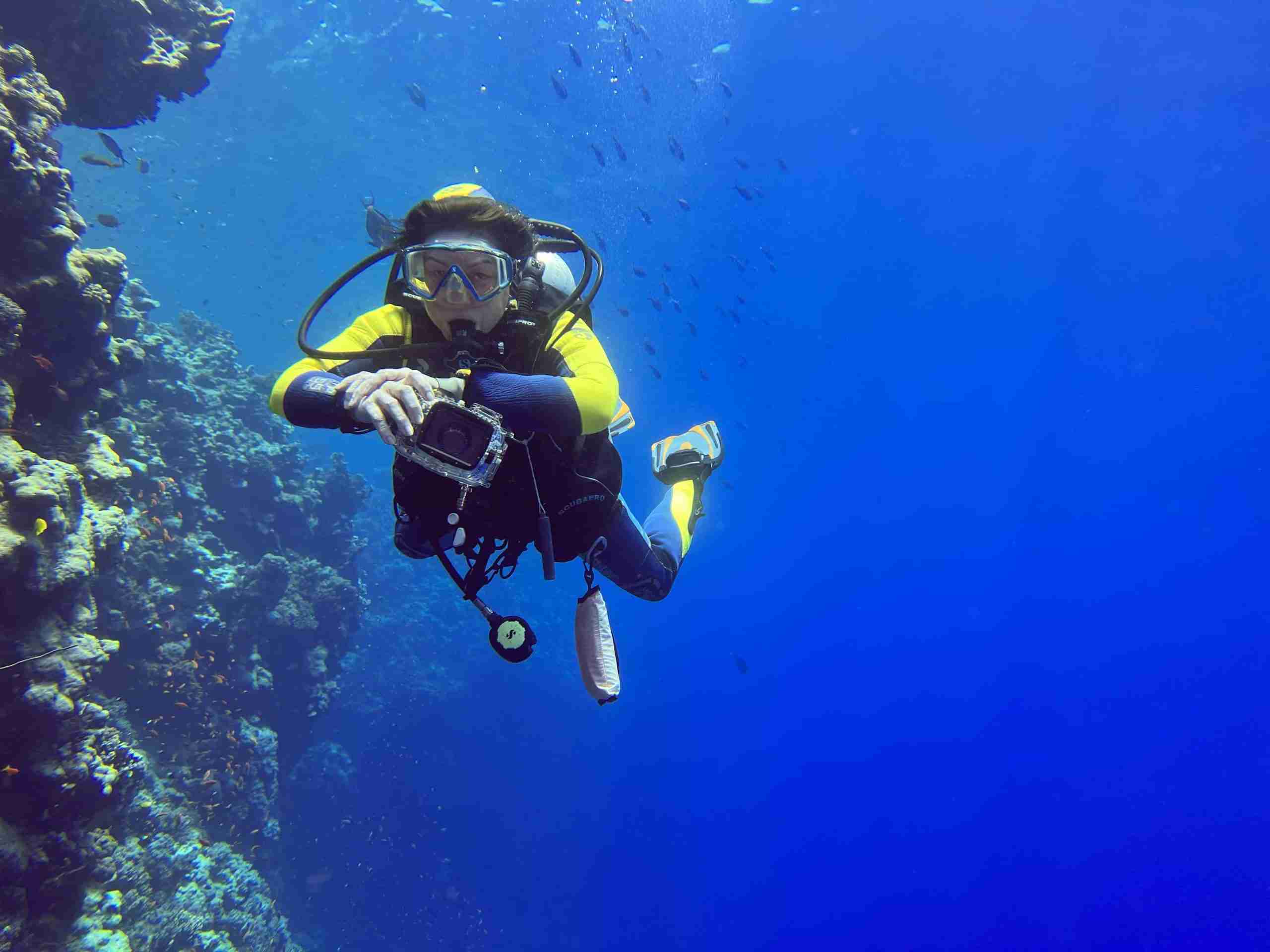 Diver holding position at the reef edge with open blue water behind